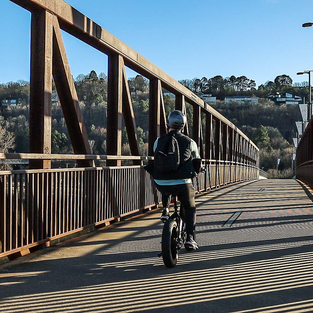 Person riding the Emerald E-bike on a bridge.