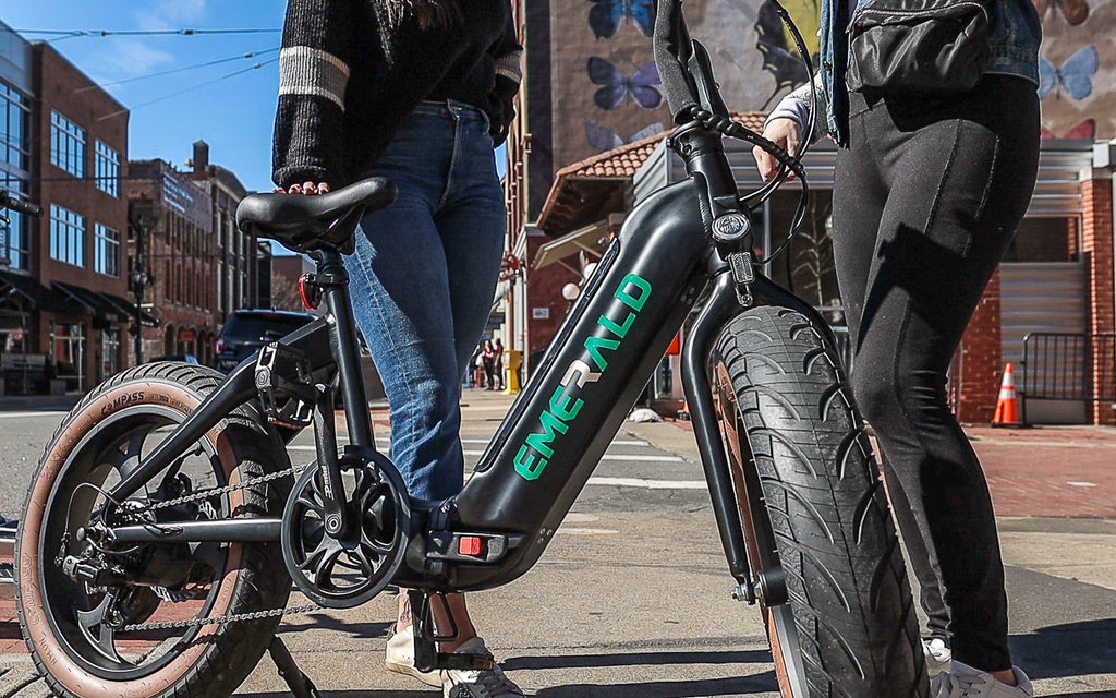 Two people standing on a street corner with the emerald ebike