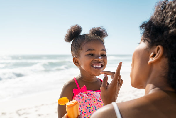 A black woman applying eco-friendly sunscreen on a child
