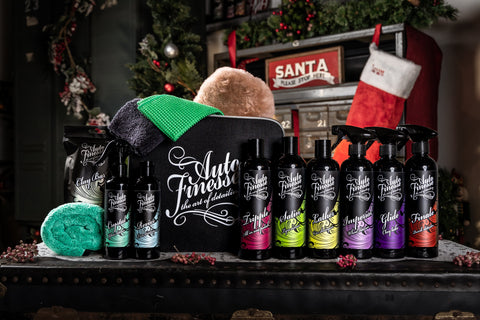 Auto Finesse detailing products laid out side by side with a kit bag inside of a setting that looks like Santa's workshop.