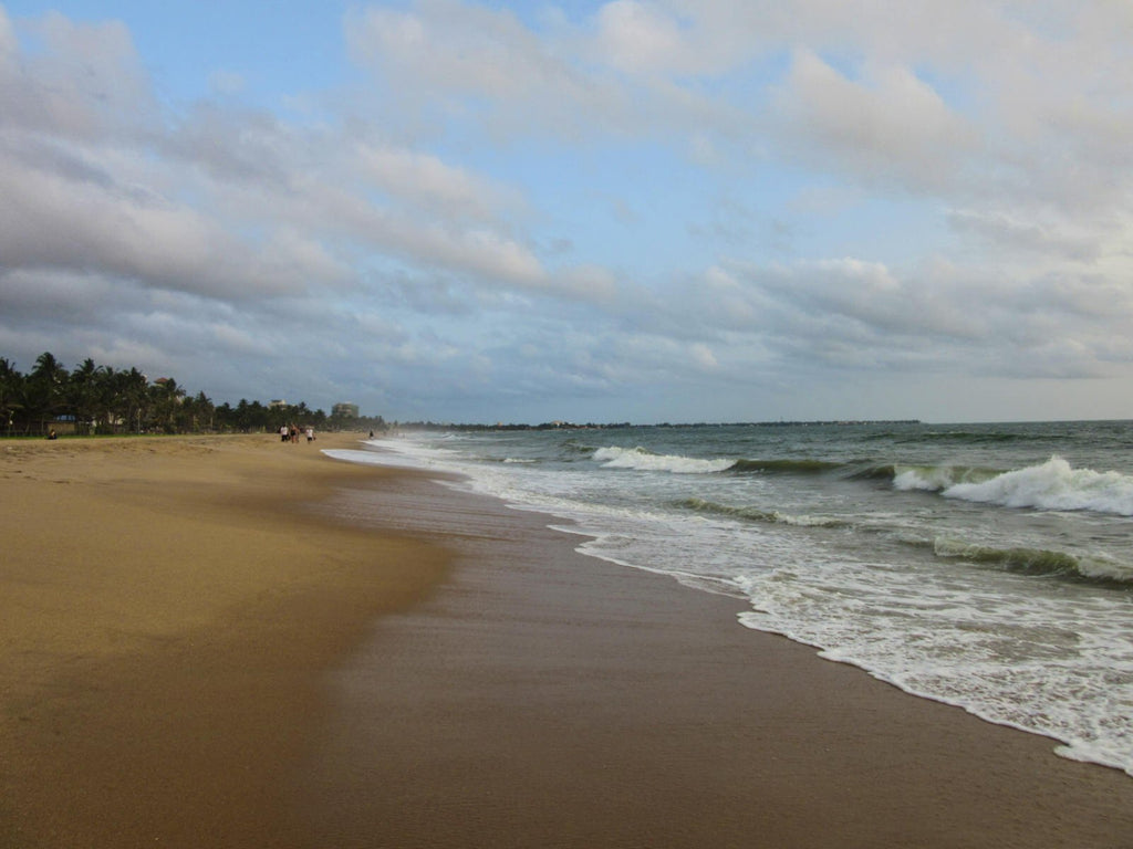 Looking along Negombo beach Sri Lanka with ocean waves rolling in.