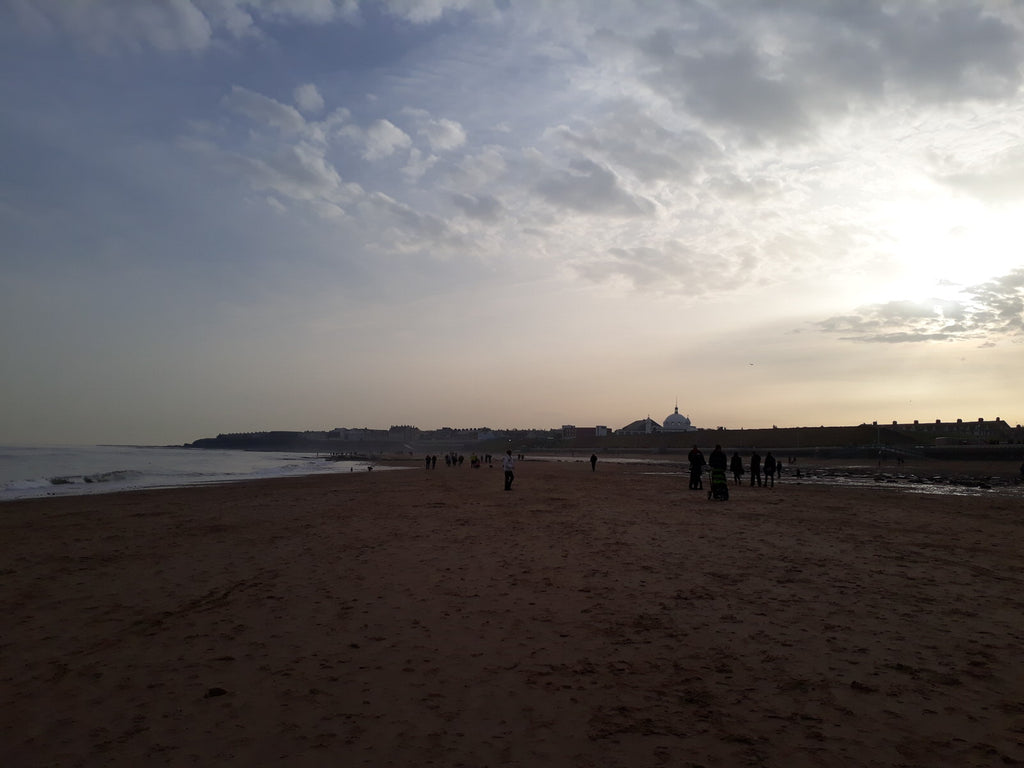 Wide sandy beach in Whitley Bay as the sun sets.