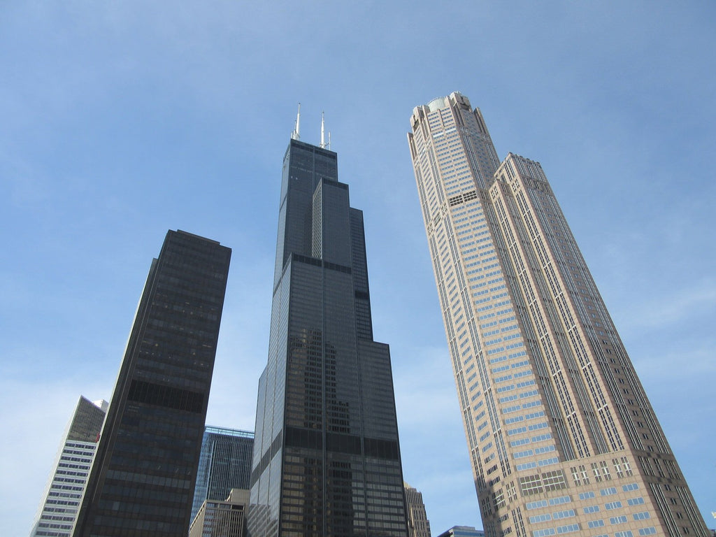 Looking up at three Chicago skyscrapers, with the Willis Tower in the centre, against a blue sky