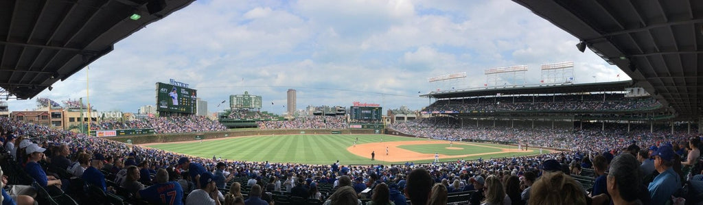 Panoramic view of Wrigley Field with full crowds and baseball game in progress.