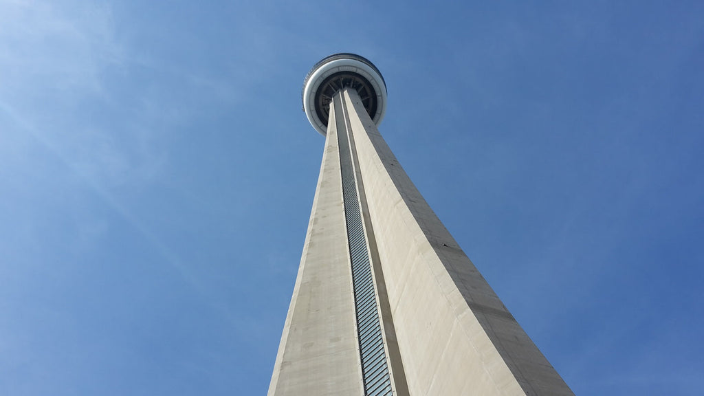 Looking up at the CN Tower in Toronto, with the structure against a blue sky.