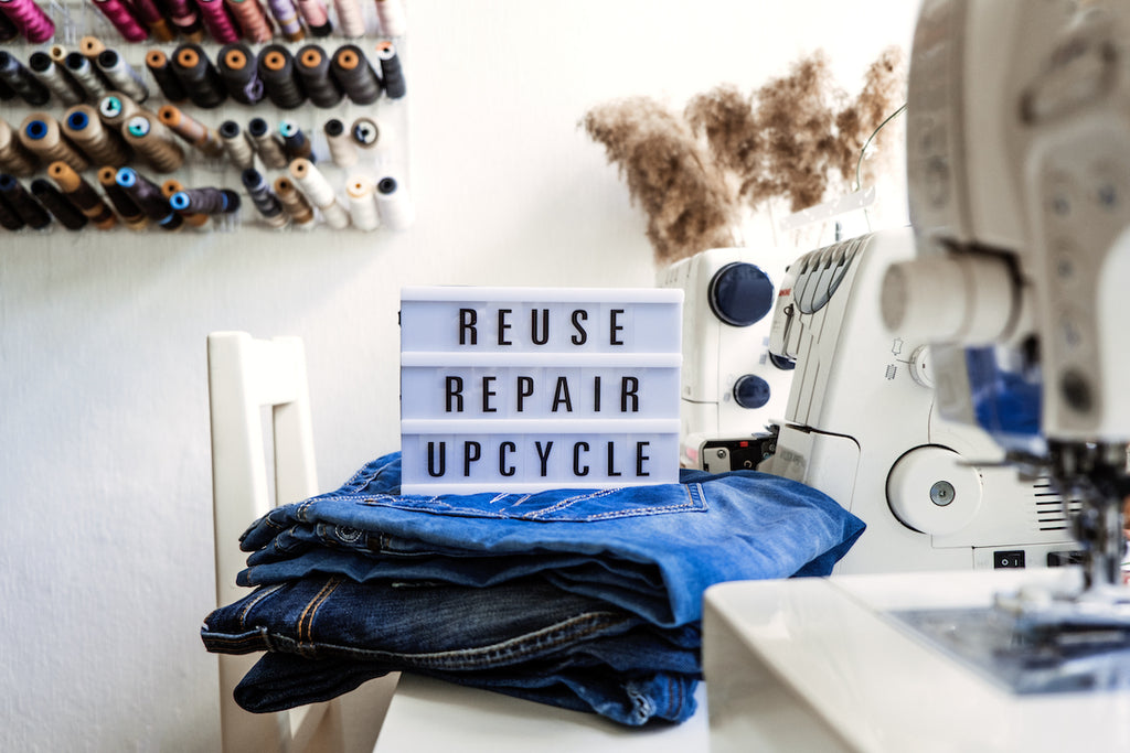 Pile of jeans with a sign that says "reuse, repair, upcycle"