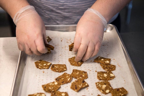 gloved hands grab and stack gluten-free cranberry almond crisps