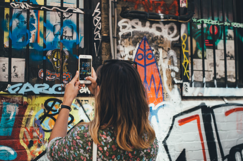 a young woman taking pictures of graffitis on a wall