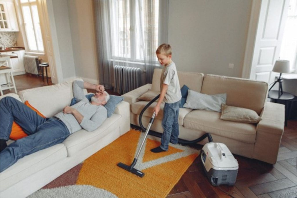 : A kid vacuuming a colourful rug in the living room