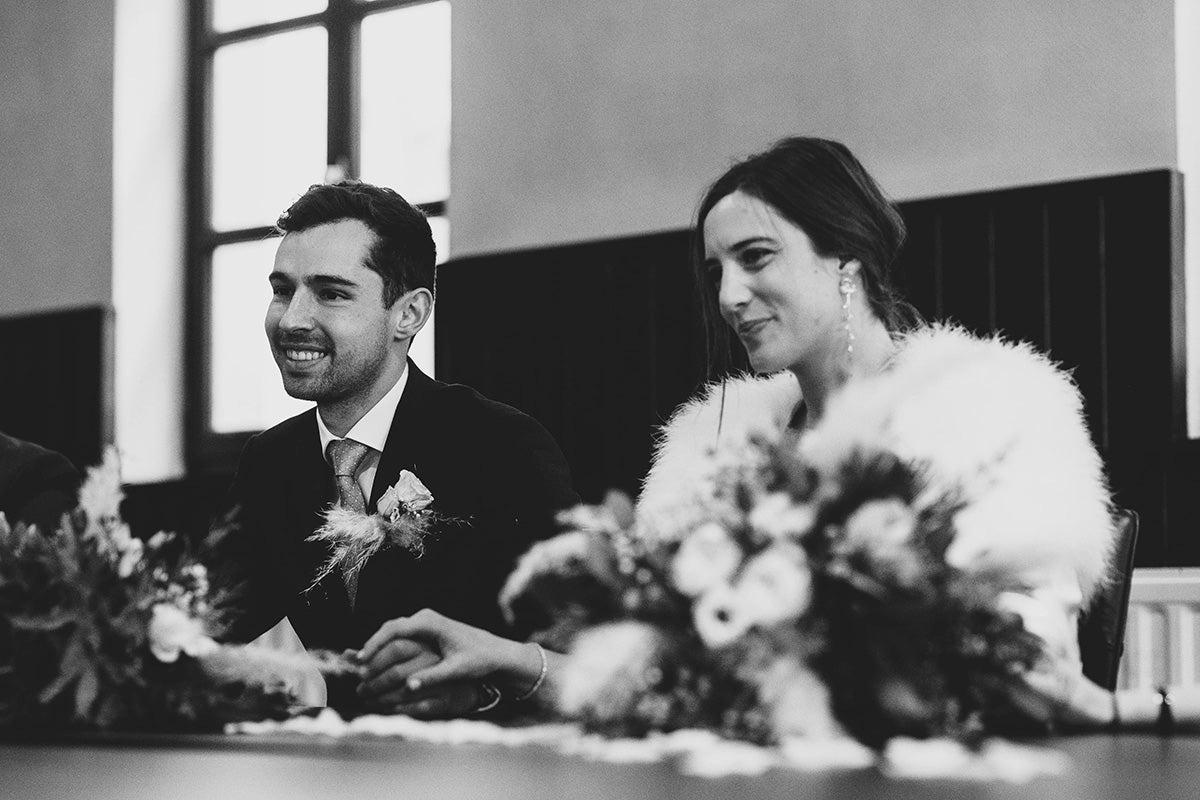 Mariées assis à une table avec des fleurs en premier plan