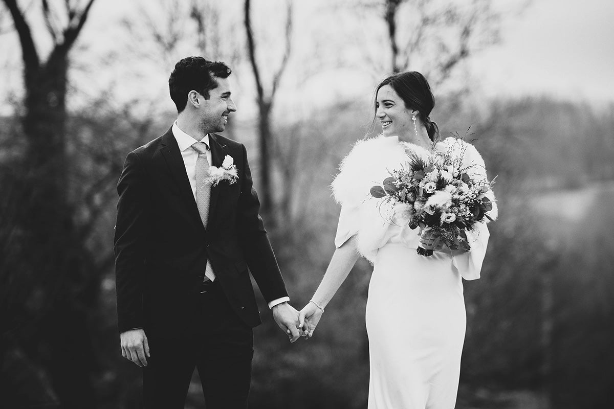 Mariées se tenant la main en souriant avec robe blanche et costume