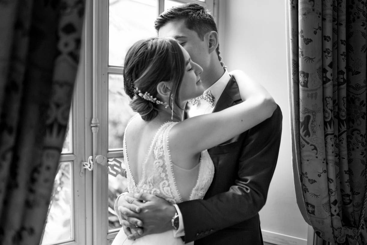 Recém-casados ​​se abraçando na beira de uma janela