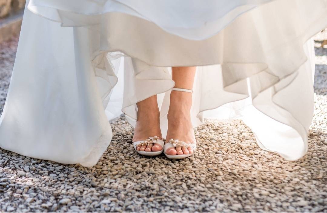 Robe de la mariée soulevée qui laisse voir ses chaussures à talon ouverte avec un clip à chaussure