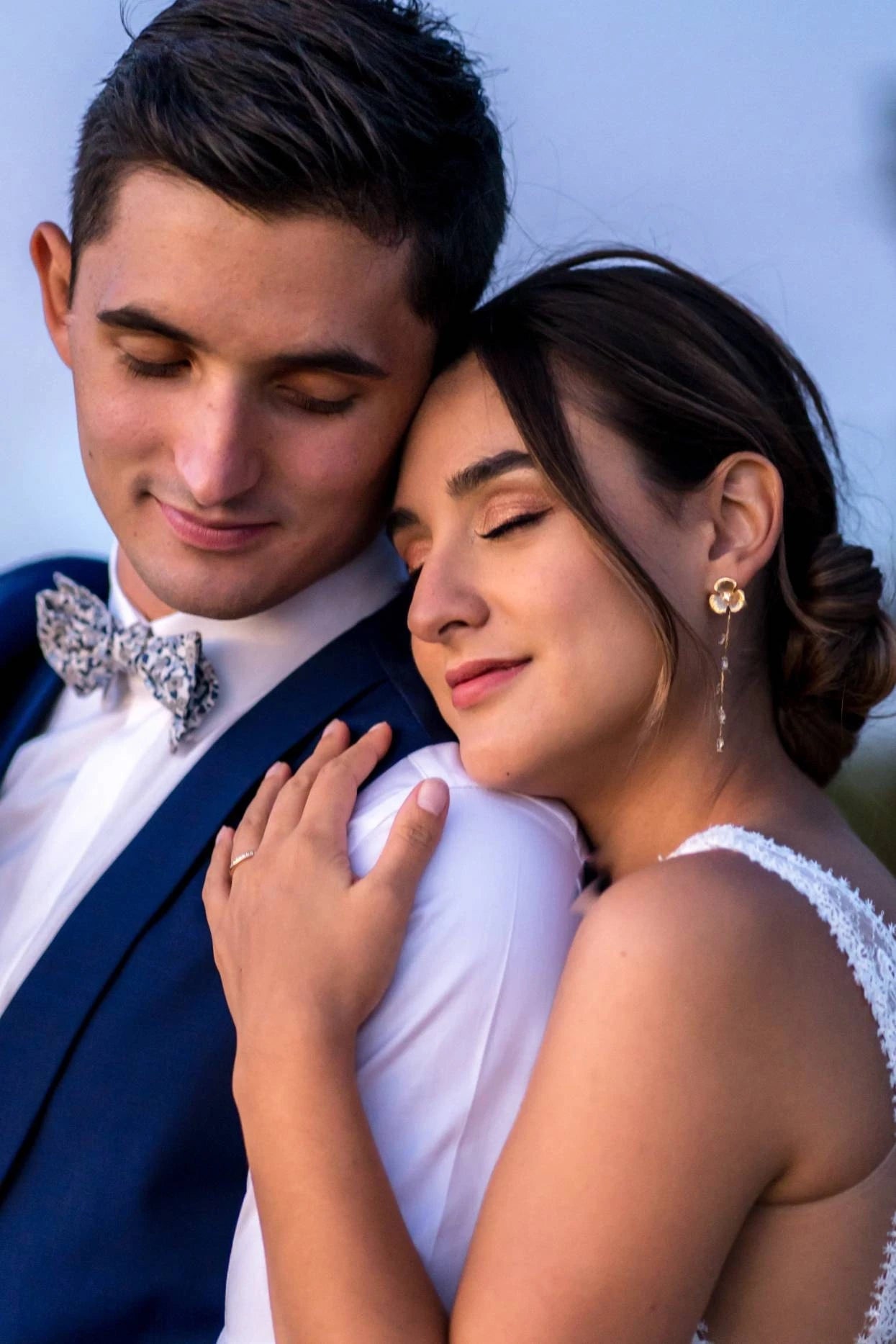 retrato dos noivos encostados no ombro olhos fechados com laço e brincos longos de flores