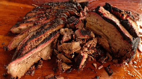 Close-up of a sliced brisket resting on a wooden cutting board, showcasing tender, juicy pieces ready for serving.