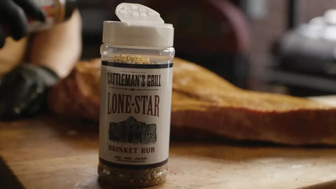 Close-up of an open container of Cattlemen's Lone Star dry rub on a wooden table, placed next to a brisket ready for seasoning.