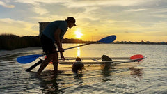 Adult pushing Aura Kayaks Adventurer Clear Kayak into the water.