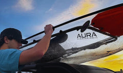 Adult transporting Aura Kayaks Adventurer Clear Kayak to car.