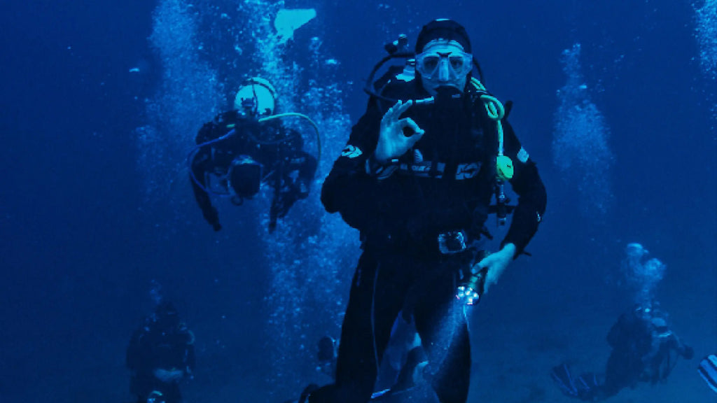 Scuba diver underwater giving "ok" hand sign.