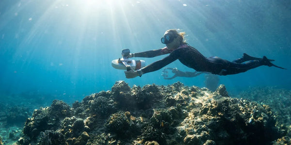 Two free divers in ocean using Sublue WhiteShark Tini underwater scooters.