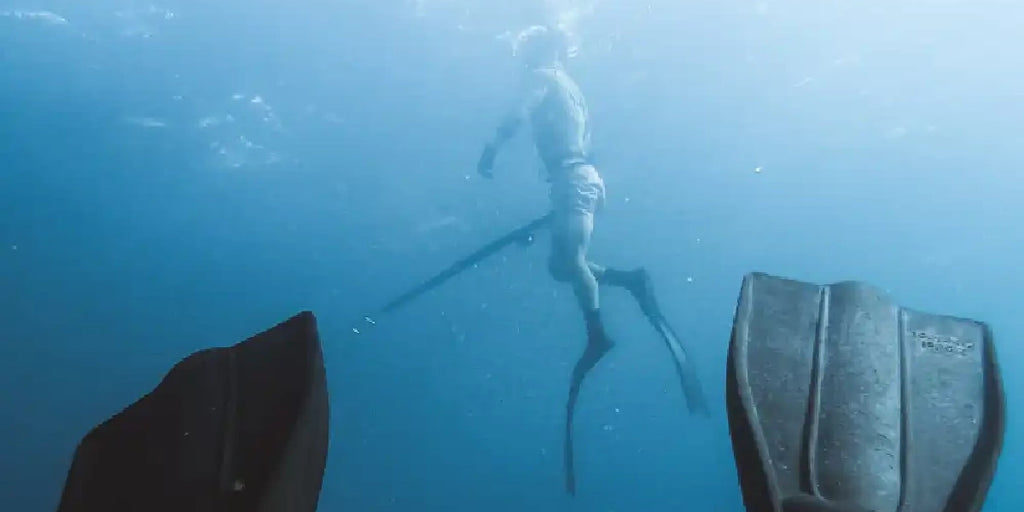 Spear fisher treading water with fins in foreground.