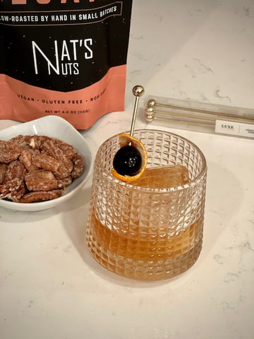 Cinnamon whiskey pecans sitting next to an Old Fashioned cocktail