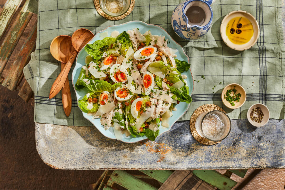 Chicken Caesar Salad in a blue serving bowl on an outdoor table