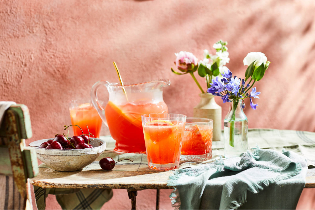 Summer grapefruit spritzer cocktail in a jug with glasses and fresh flowers