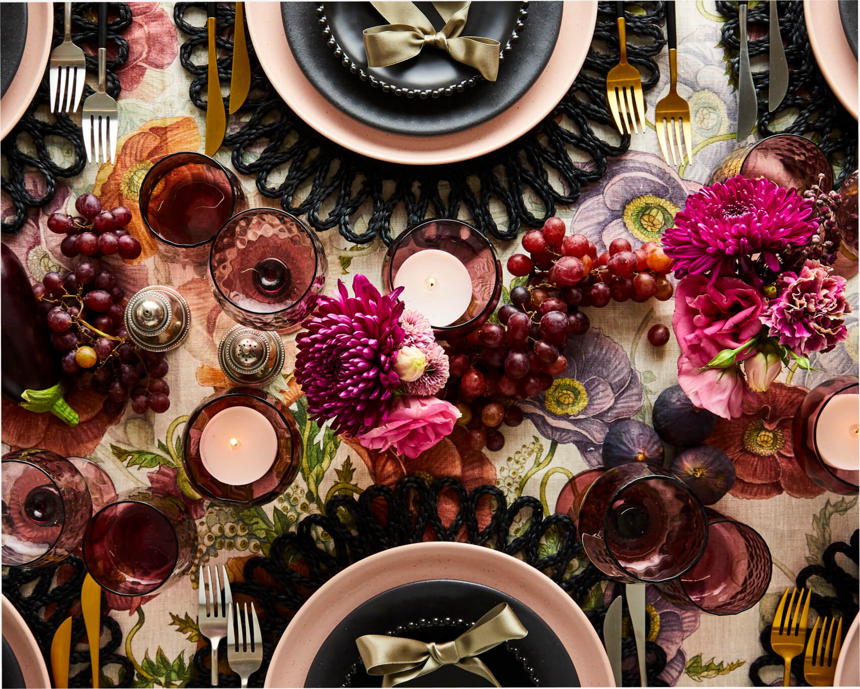 Autumnal tablescape with purple and pink flowers and candles, black, pink, gold.