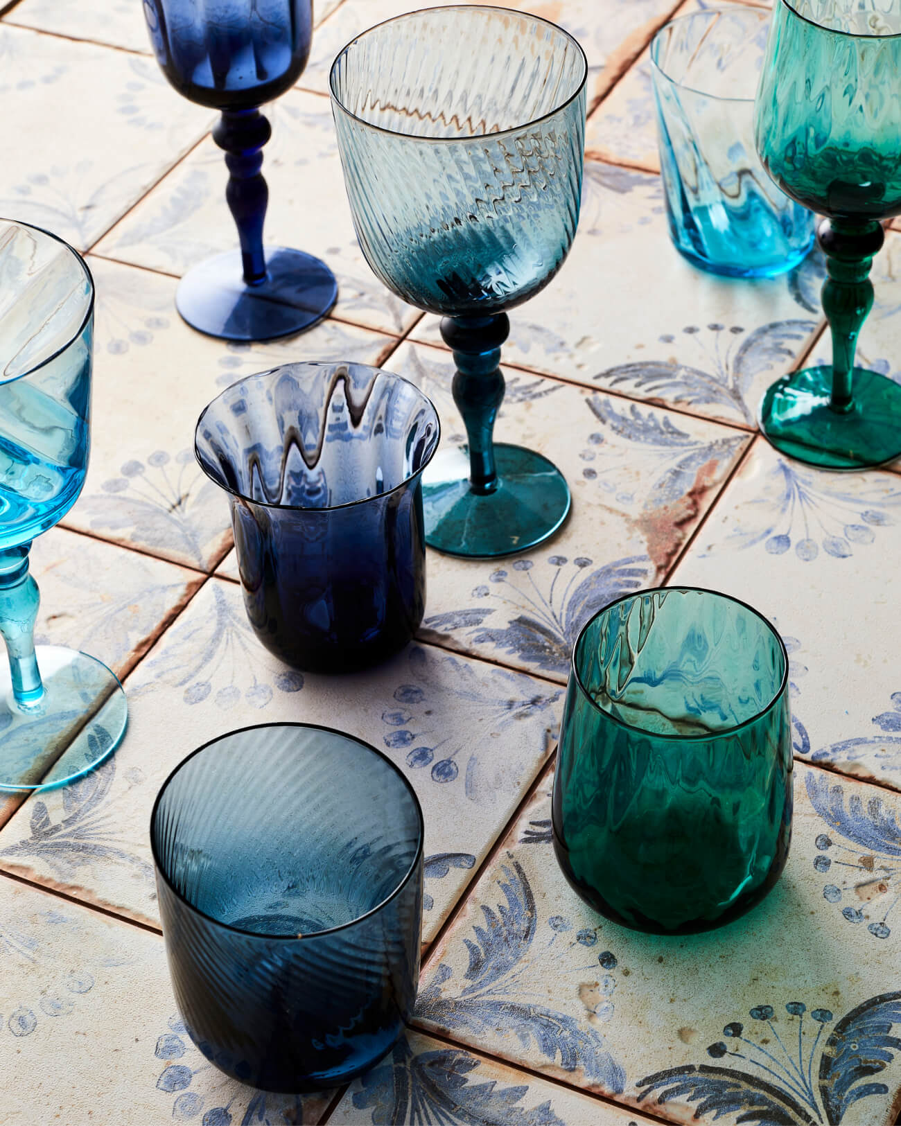 Selection of beautiful ornate mix and match blue glassware photographed on tiles