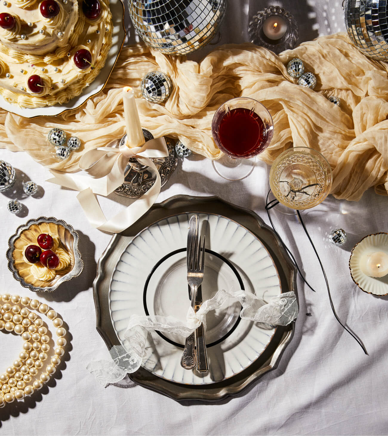 Vintage inspired New Year's Eve tablesetting with disco glamour, vintage glassware, elegant white candles and ivory ribbons from The Social Kitchen