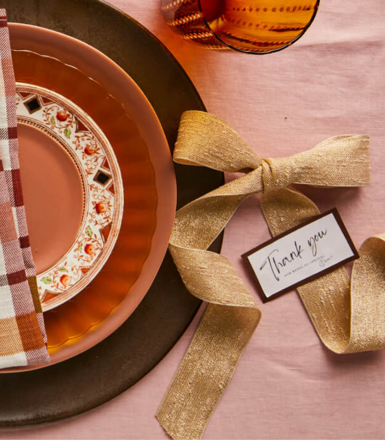 Thanksgiving place setting inspiration with gold ribbon and name tags alongside orange, brown and pink plates