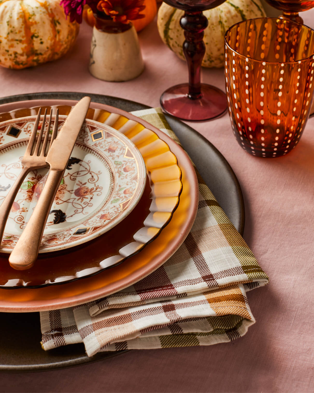 Thanksgiving place settings with a mixture of vintage and modern crockery and glassware in orange, brown and pink