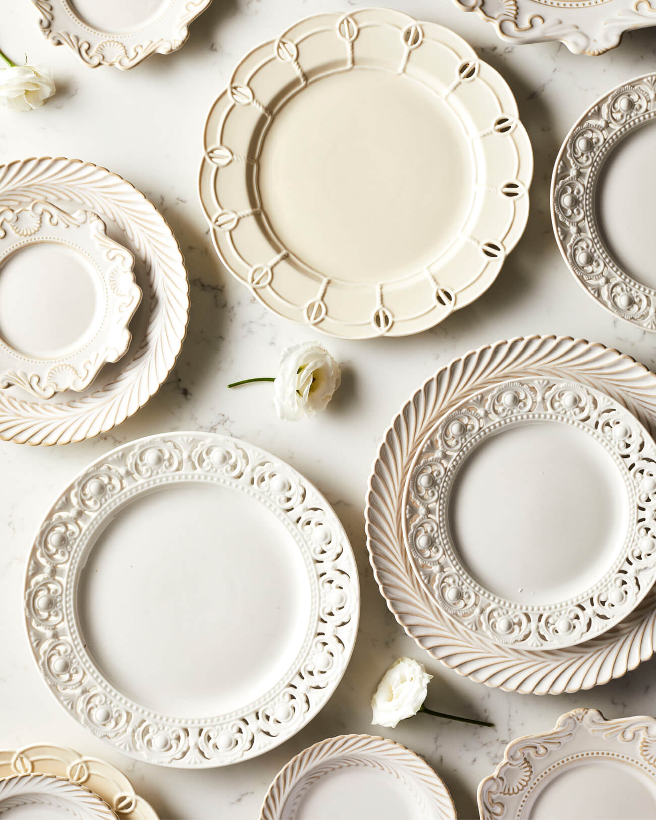 Multiple white and cream mix and match plates next to one another on a table, vintage, lace, crockery