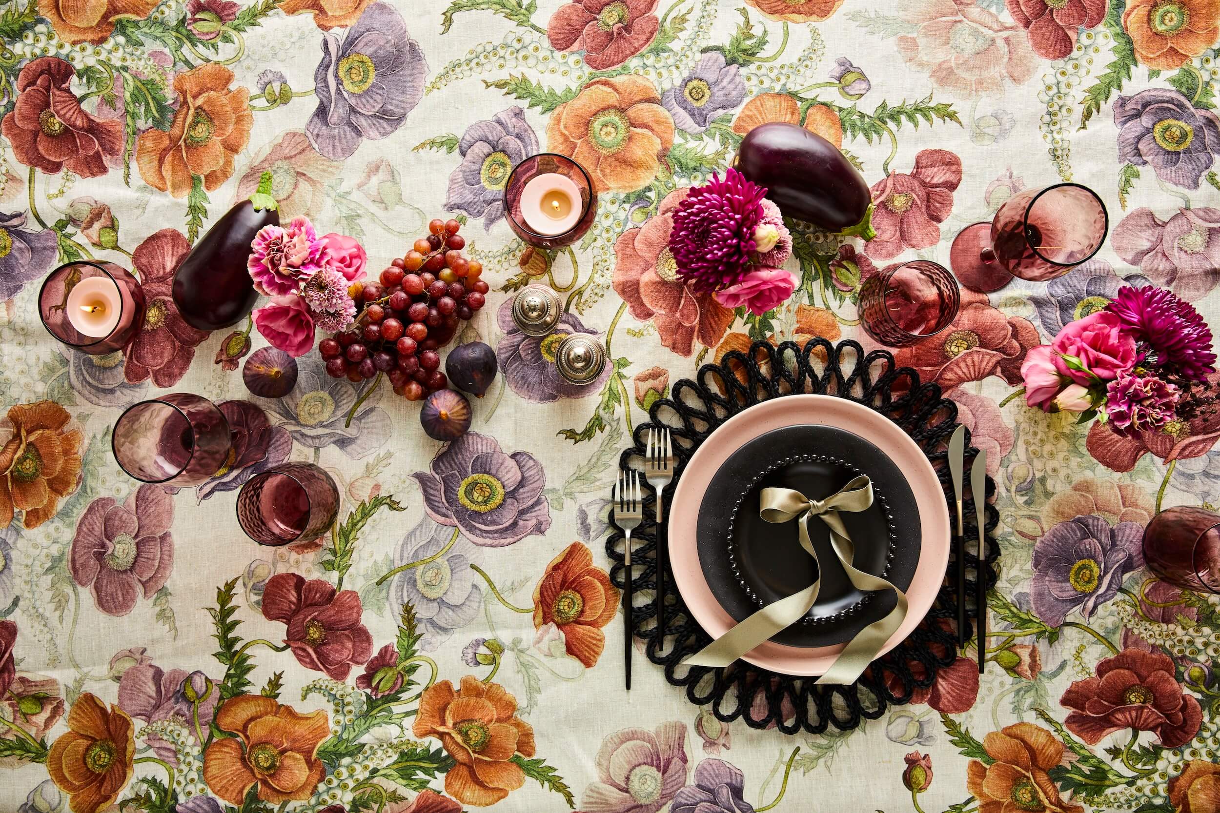 Autumnal tablescape with black, pink and purple crockery and glassware on a floral tablecloth