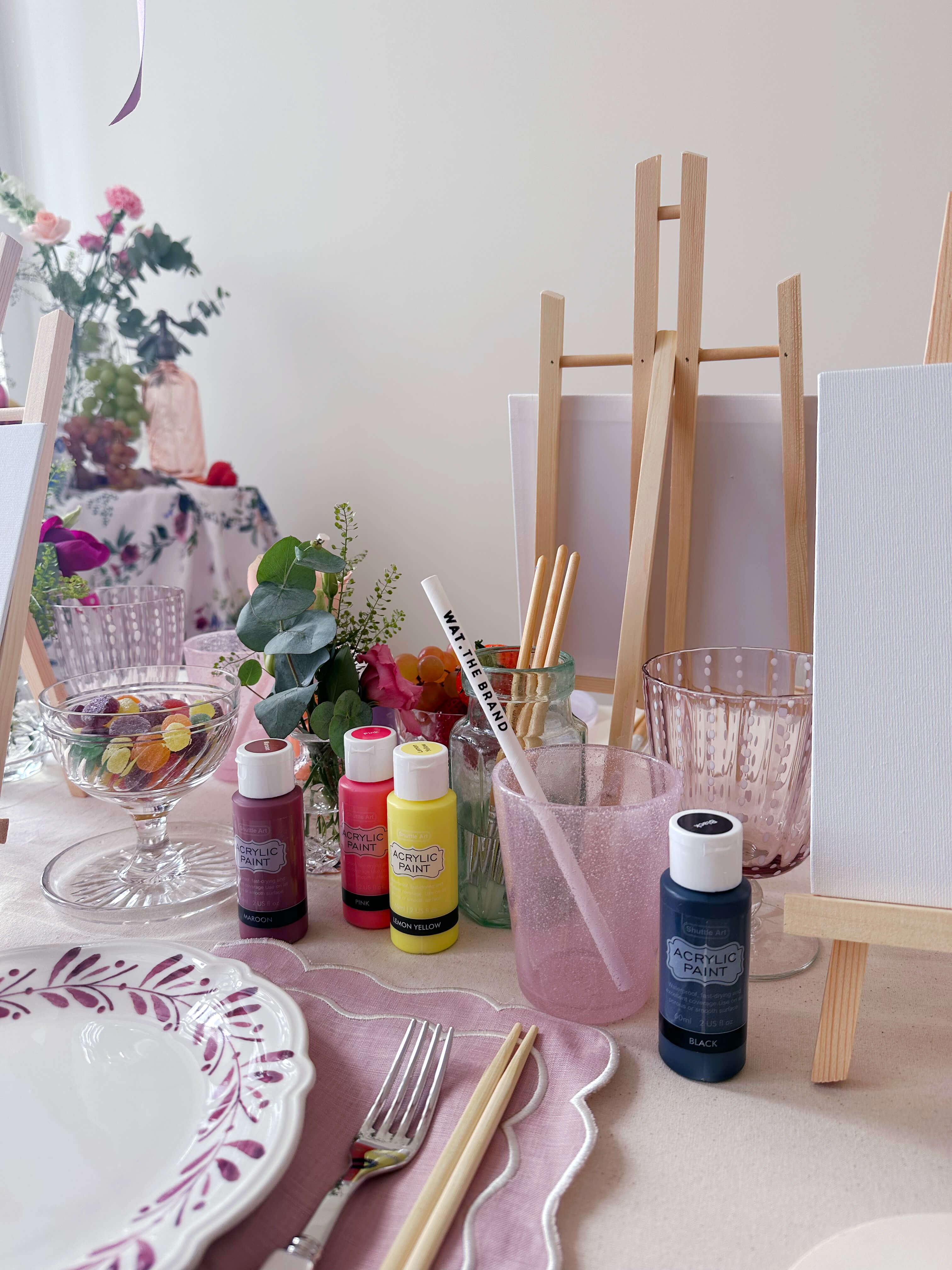 Close up of a place setting with easel, plate and paints along with other ornaments