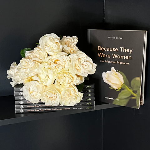 A stack of Because They Were Women on a black shelf with white roses next to an upright copy of the book.