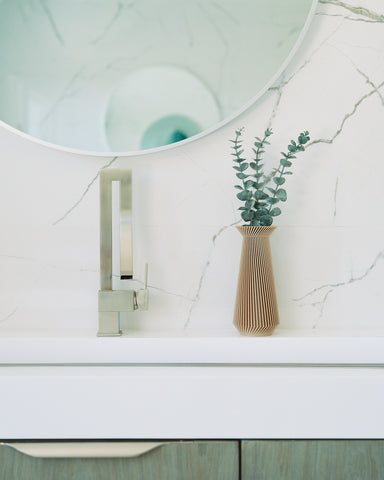 A neutral vase / modernist vase by Woodland Pulse sitting on a marble sink countertop.