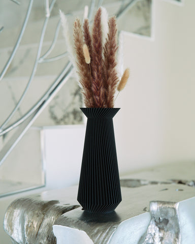 A black vase by Woodland Pulse on a marble countertop. This is a beautiful modern black vase.