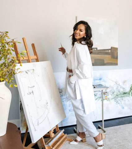 A photo of Huda Hashim, a renowned artist and designer in front of a canvas. Photo posted by home decor retailer Woodland Pulse.