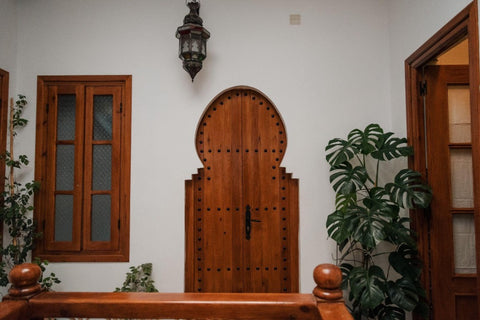 Entrance wood door with monstera deliciosa plant on patio.