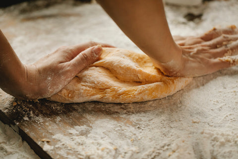 a woman's hands kneading dough on a floured surface