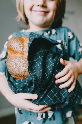 A small child holding a rather large loaf of bread