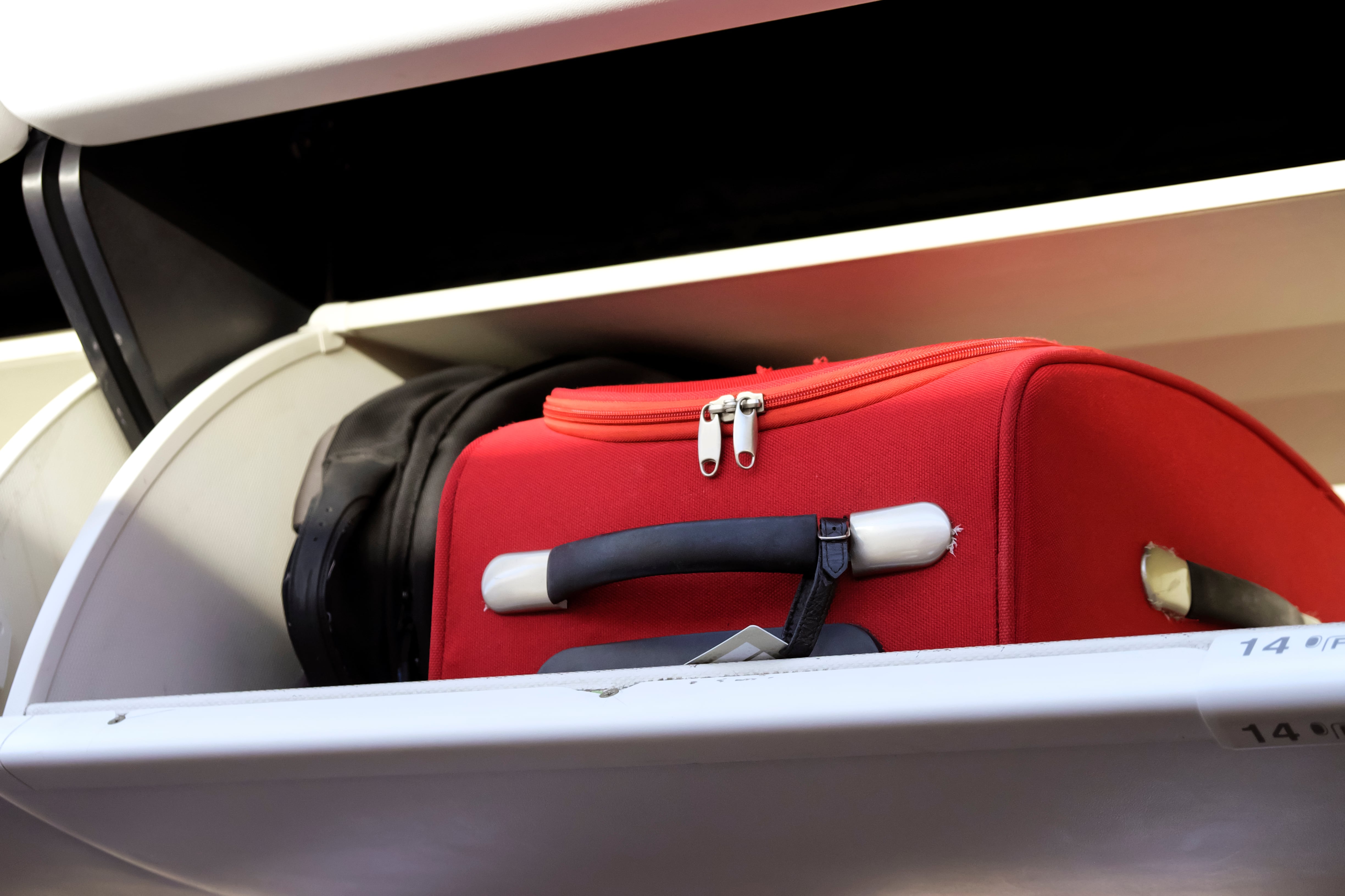 Compact suitcase placed in an airplane overhead bin, illustrating travel readiness.
