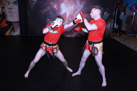 A photo of Mick Crossland holding pads for advanced kickboxing drills