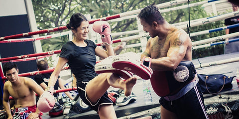 A photo of Trainer Gae and a student demonstrating pad work at Elite Fight Club, one of the best Bangkok Muay Thai gyms in Thailand