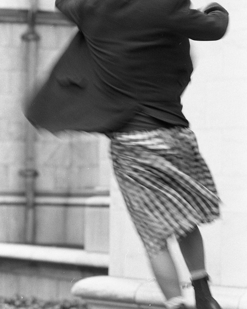 Keanu Reeves in Toronto, Ontario, in a blurry jump, in black suit jacket and plaid skirt.