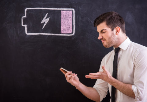 Angry young man is holding his smartphone with battery low.