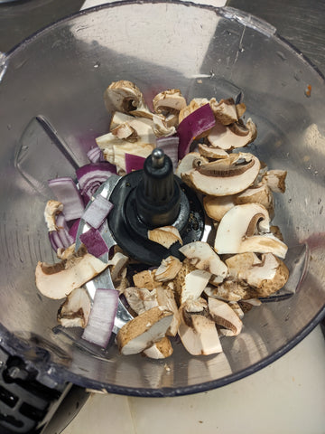 image of mushrooms and onions in food processor bowl -- the recipe calls for this mixture to be reduced to small bits and then sauteed in a hot pan for several minutes
