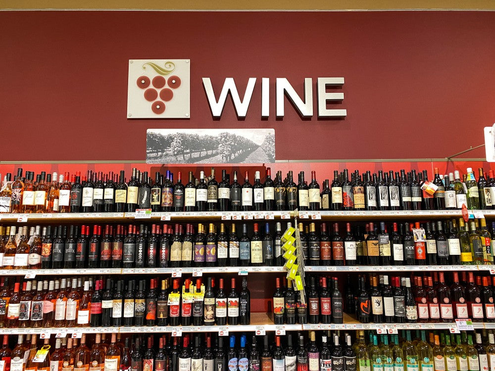 A wide selection of wine is visible in a grocery store wine aisle